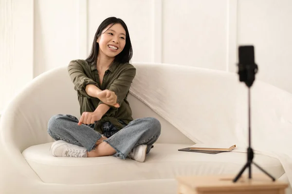 ブログ ブログの概念 非常に若いです中国の女性でカジュアルな座っていますソファに足を上げます スマートフォン上のフォロワーや友人のためのビデオを記録します 家のインテリア コピースペース — ストック写真