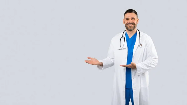 医療広告 積極的な男性医師Poinsideにフリースペースで二つの手 中年医師男で制服を着て上の灰色の背景 パノラマとともにフリー場所のためにデザイン — ストック写真