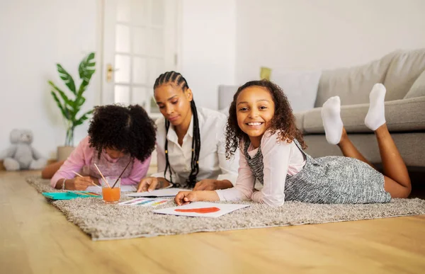 快乐的非洲裔美国女孩和妈妈一起画画 妹妹在家里共度周末 躺在地板上 微笑着拍照 家庭大厅 选择性焦点 — 图库照片