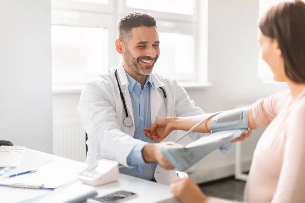 妊娠期高血压男医生用袖口测量年轻孕妇的动脉血压 坐在诊所办公室 保健概念 — 图库照片