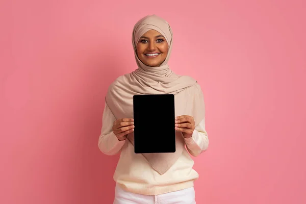 用空白黑屏 快乐的伊斯兰女性头戴头巾展示应用程序或网站设计的复制空间 粉红背景 调校等 在希贾布手持数码桌面上微笑穆斯林女性 — 图库照片