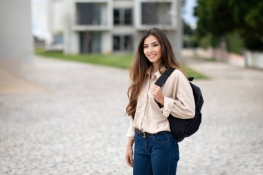Sırt çantalı neşeli, oldukça zeki genç Avrupalı bayan öğrenci üniversite, açık hava, boş alan derslerine gidiyor. Modern eğitim, öğrenim, bilgi, lise ve yaşam tarzı