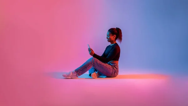Lenyűgöző Boldog Fekete Hölgy Használja Okostelefon Stúdió Háttérben Neon Fény — Stock Fotó