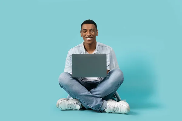 Щасливий Тисячолітній Чорний Хлопець Сидить Підлозі Використовує Ноутбук Ізольований Синьому — стокове фото