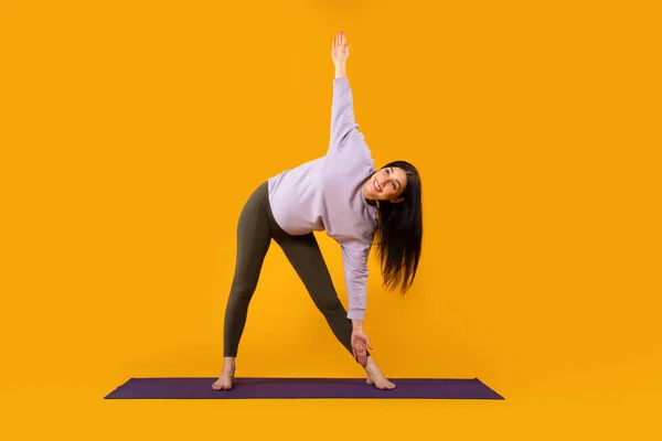 怀孕瑜珈和健身的概念 年轻的孕妇在黄色工作室的背景下进行锻炼 伸展腿和双手 体长全长 — 图库照片