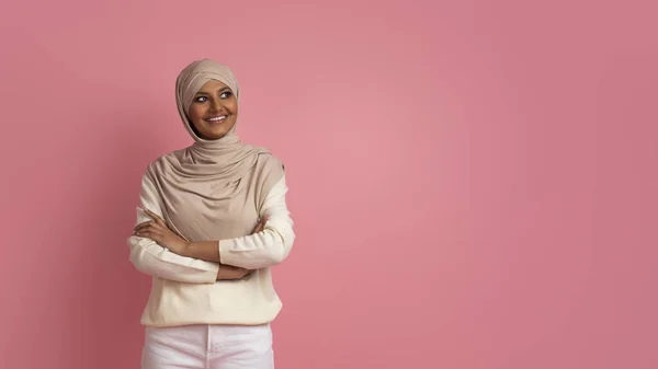 希贾布年轻穆斯林妇女的画像 带着兴趣望着复印空间 微笑着 头戴头巾 双手交叉地站在粉红工作室的背景下 — 图库照片