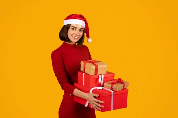 클로스가 크리스마스 선물을 모자를 멋지게 미소짓는 오렌지 스튜디오 위에서 Xmas — 스톡 사진