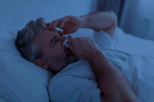 中年白发病人穿着睡衣 用餐巾纸触摸流鼻涕 晚上在床上打喷嚏 摸着头 头皮炎的特写镜头 — 图库照片