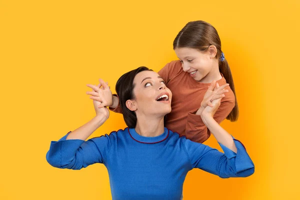 可爱的小女孩在玩猜谁时让妈妈吃惊 快乐的年轻妈妈 在黄色工作室的背景下在一起玩乐的未成年女孩 复制空间 — 图库照片