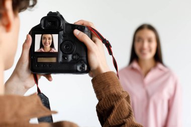 Fotostudio 'da genç güzel bir kadının fotoğrafını çeken fotoğrafçı, fotoğraf çekimi sırasında çalışan dijital kameraya odaklan, bulanık arkaplan