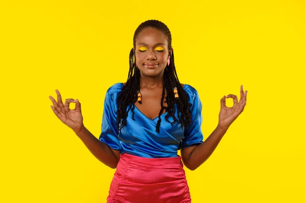 平静的非洲裔美国女人闭着眼睛做欧米茄冥想站在黄色的背景上做瑜伽 沉着与心神的概念 Studio Shot — 图库照片