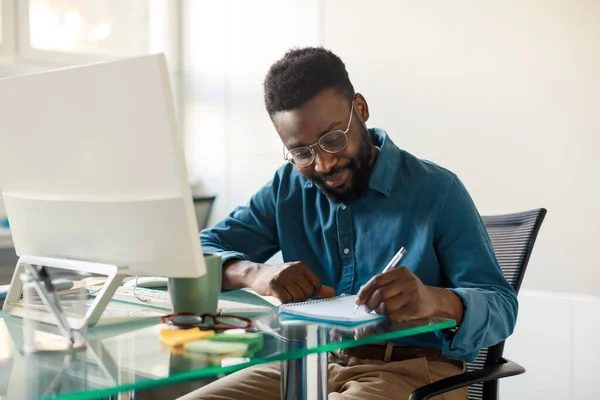 Μαύρος Επιχειρηματίας Που Εργάζεται Στο Γραφείο Και Κρατά Σημειώσεις Κάθεται — Φωτογραφία Αρχείου
