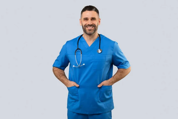 Portret Pozytywnego Lekarza Lub Pielęgniarki Pozujących Rękami Kieszeniach Uśmiechających Się — Zdjęcie stockowe