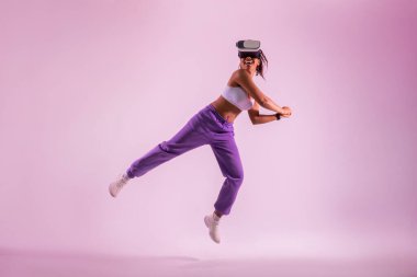 Sanal gerçeklikte tenis oynayan sportif siyahi kadın, Google 'da sanal tenis sopası sallayan kadın, pembe neon stüdyo arka planı, tam boy.