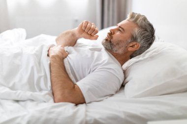 Kronik öksürük, sebepler ve tedavi. Sağlıksız, hasta, gri saçlı, orta yaşlı, pijama giymiş, öksüren, ev içi, yan görüş, fotokopi odası