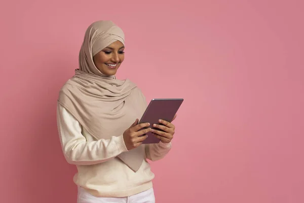 用数字表格 在线购物或浏览社交网络 头戴头巾的阿拉伯女性享受现代技术 站在粉红工作室的背景下微笑穆斯林女性 — 图库照片
