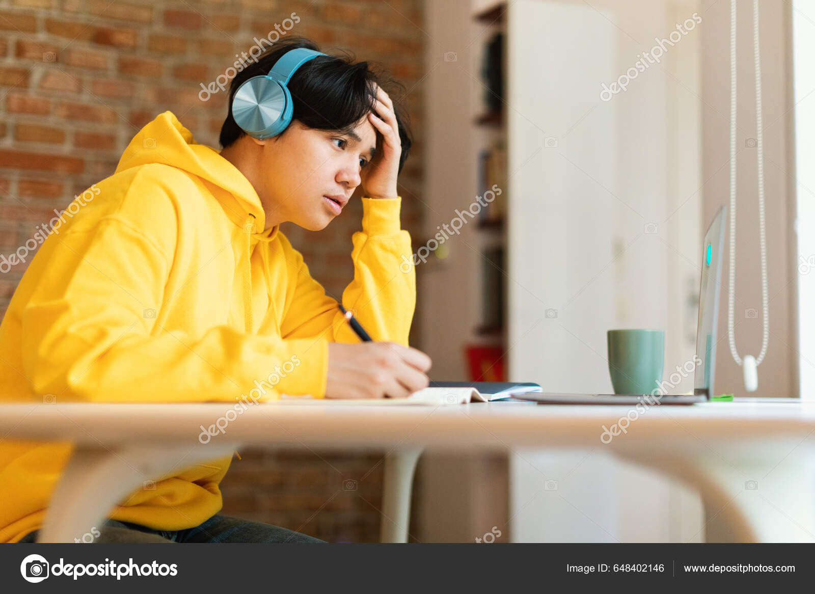 Um menino com fones de ouvido está sentado em um computador