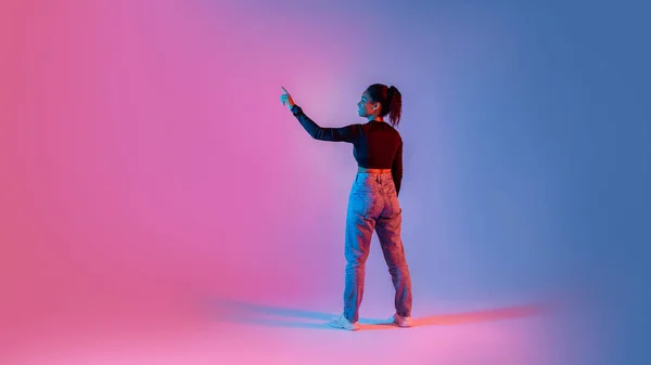カラフルなネオンの背景 パノラマ コピースペース上の仮想インターフェイスを使用して 想像上の画面に触れる黒の女性のバックビュー ボタンを押してください 現代技術の概念 — ストック写真