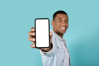 Mavi stüdyo arka planında boş ekranlı akıllı telefon gösteren kendine güvenen siyah bir erkek görmek güzel. Duygu, sunum uygulaması, aygıt, öneri satışı, web sitesi