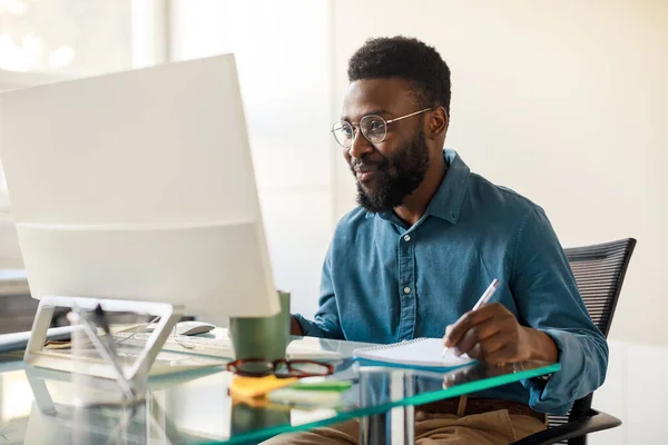 Feliz Empresario Afroamericano Sentado Mesa Trabajo Mirando Pantalla Computadora Tomando —  Fotos de Stock