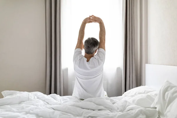 Вид Сзади Неузнаваемого Седого Мужчину Пижаме Сидящего Кровати Растягивающего Тело — стоковое фото