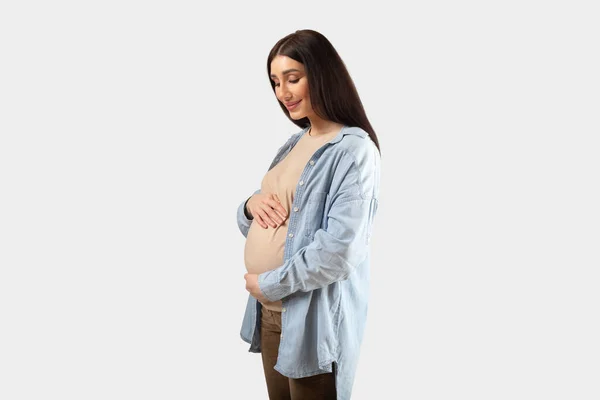積極的な若いです妊娠中の女性を受け入れ腹と笑顔 美しいです女性期待赤ちゃん Tenderly Touch彼女のおなか 上の白いスタジオの背景 — ストック写真