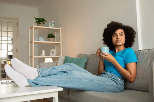 Pensativo Milenario Afroamericano Rizado Dama Disfrutar Relajarse Una Taza Sofá —  Fotos de Stock