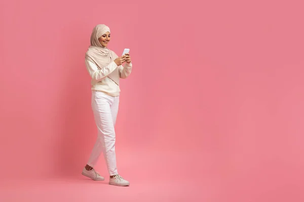Komunikasi Seluler Smiling Muslim Woman Hijab Walking Smartphone Pink Background — Stok Foto
