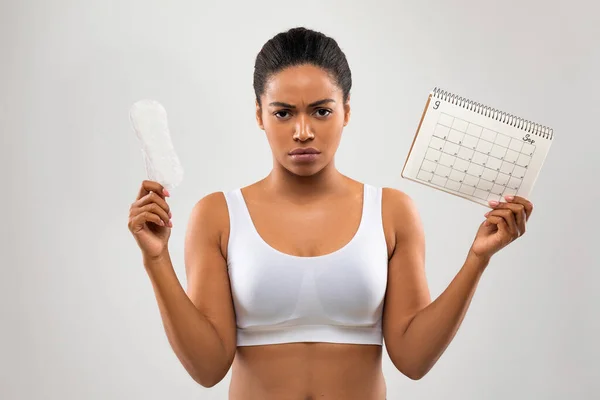 Zły Nieszczęśliwy Młoda Czarna Kobieta Demonstruje Kalendarz Okresów Higieniczne Serwetki — Zdjęcie stockowe