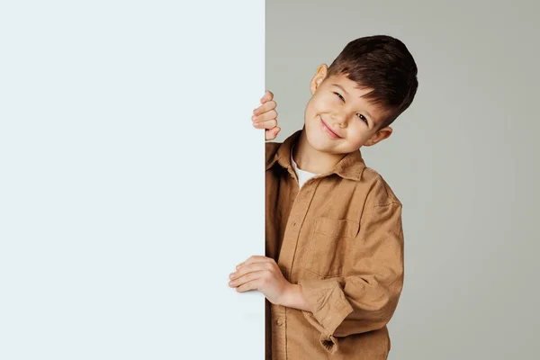 笑顔の白人6歳の男の子は 灰色のスタジオの背景に隔離された空白のスペースを持つ大きなバナーでカジュアルです 子供の感情 子供時代とライフスタイルのための広告と提供 — ストック写真