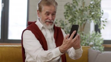 Sanal aile toplantısı. Akıllı telefondan video çağrısına olumlu cevap veren ve torunlarıyla konuşan, evde dinlenen, çekim takip eden, yavaş çekim, serbest alan