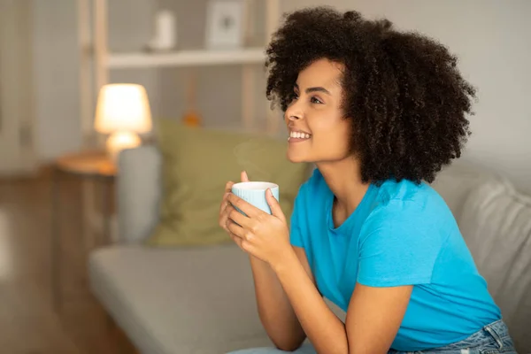 Glad Millennial African Curly Lady Enjoy Relaxing Cup Tea Sofa — стоковое фото