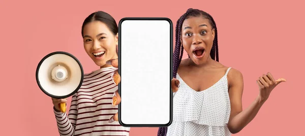 素晴らしい提案だ メガホンを使用して ホワイトスクリーンで大きな空白のスマートフォンを表示する2人の多民族女性 スピーカーと広告の新しいアプリで発表を行う多文化女性 モックアップ — ストック写真