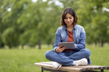 Gülümseyen Arap Kız Öğrenci Dijital Tablet ile Dinleniyor, Mutlu Milenyum Orta Doğu Kadını Dışarda Oturuyor ve Modern Gadget, Çalışma Alanını Çevrimiçi veya İnternet Taraması Kullanıyor