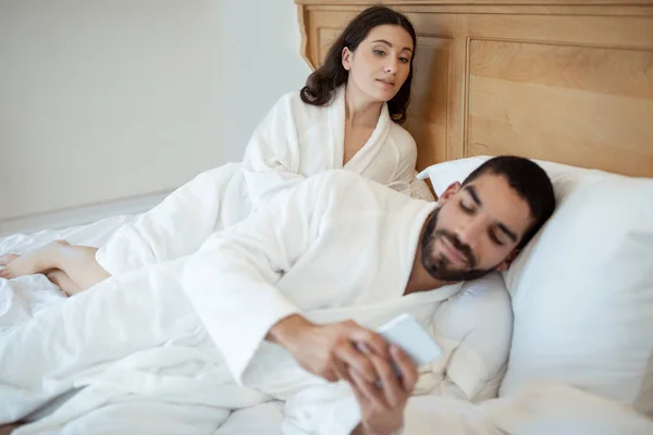 Kocasının Evde Yatakta Yatarken Akıllı Telefondan Mesaj Attığından Şüphelenen Kıskanç — Stok fotoğraf