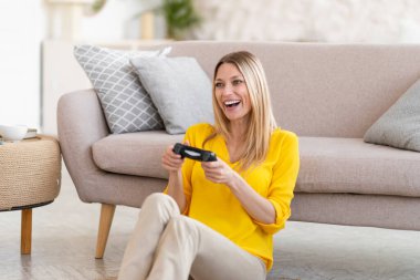 Binlerce yıllık beyaz, sarı elbiseli, elinde joystick olan sarışın bayanın oturma odasında boş vakitlerinde bilgisayar oyunu oynamasına gülerek. Evde tek başına kazan ve eğlen, eğlence