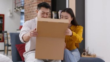 Kötü teslimat servisi. Karton kutuları düzen içinde açan evli bir çift ve mahvolmuş ürünleri görüyorlar, mutsuz ve üzgün hissediyorlar, evde birlikte oturuyorlar.