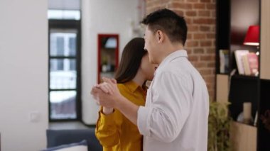 Aile içi romantizm. Mutlu Asyalı karı ve kocanın evde dans ederken çekilmiş mutlu bir portresi. Yavaş müziğin tadını çıkarıyorlar. Yıldönümünü birlikte kutluyorlar.