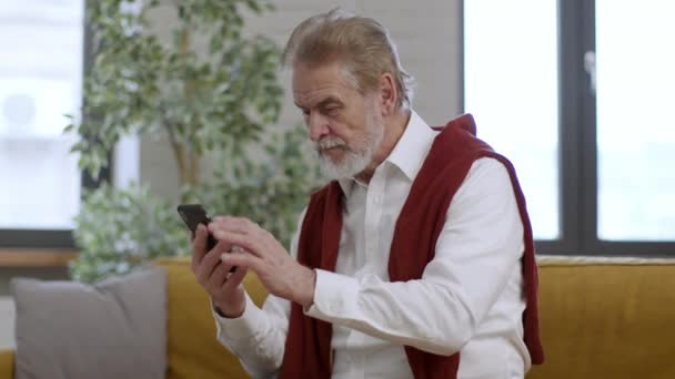 Stárnutí Zdravotní Problémy Senior Vousatý Muž Web Surfování Smartphonu Doma — Stock video