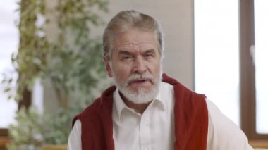 Çevrimiçi danışmanlık. Emekli, sakallı, abonelerle konuşan, yurtiçinde video blogu kaydeden yaşlı adamın pov portresi.