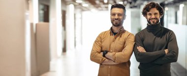 Güler yüzlü güçlü Avrupalı gençler, fabrikanın iç kısımlarında göğsünde çapraz kollar olan iş adamı mühendisler, boş alan, panorama. Takım çalışması, üretim, profesyonel çalışma