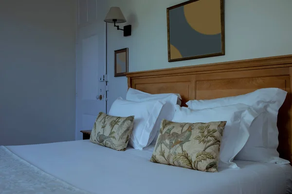 用白色毛毯装饰的带木床的卧室的内部和家里的枕头 墙上挂着抽象图片的睡房的微光镜头 没有人 现代设计理念 — 图库照片