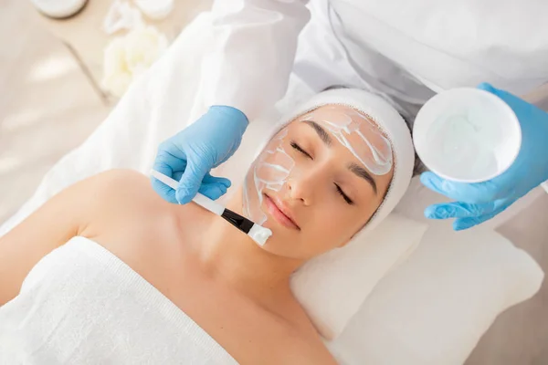 Hautpflege Kosmetikerin Die Feuchtigkeitsmaske Auf Das Gesicht Der Schönen Jungen — Stockfoto