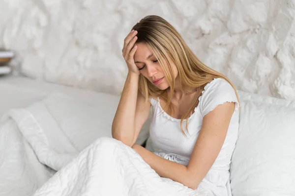 绝望的千年期白人金发女人手握双手坐在床上 患有偏头痛和白内障 感冒和流感症状 健康问题 抑郁症 — 图库照片