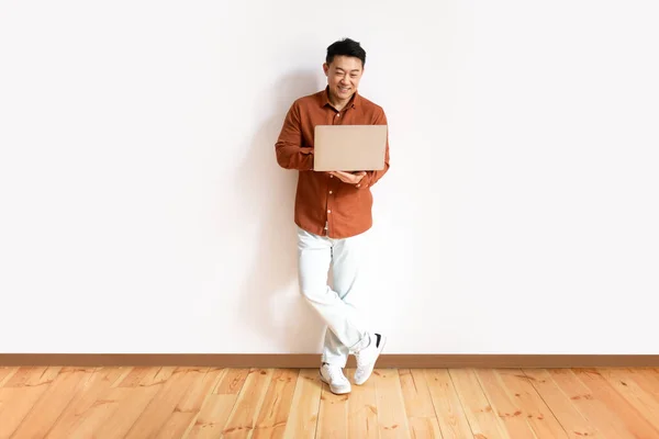 Повнометражний Знімок Веселого Азіатського Чоловіка Повсякденному Вбранні Використанням Ноутбука Онлайн — стокове фото