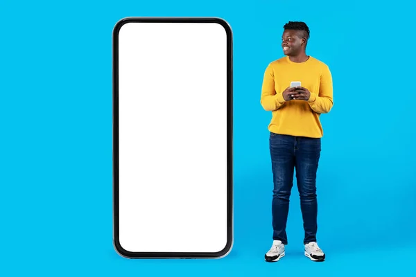 Usmívající Černošky Muž Drží Smartphone Při Pohledu Obrovské Prázdné Mobilní — Stock fotografie