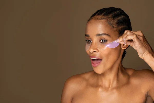 Spännande Afrikansk Amerikansk Kvinna Tar Hydrogel Ögonlappar Står Isolerad Brun — Stockfoto