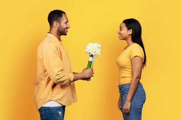 快乐的千年非洲裔美国男人送给女人一束鲜花 祝贺你生日快乐 周年纪念日在黄色的工作室背景上被隔离 恋爱和约会 — 图库照片