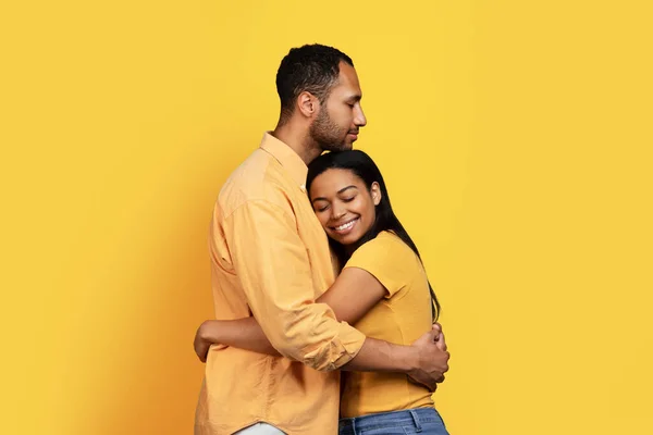 欢愉的千年非洲裔美国家庭在随意的拥抱中 享受着温馨浪漫的时刻 在黄色的工作室背景下与世隔绝 关系和爱情 生活方式 广告和提供 — 图库照片