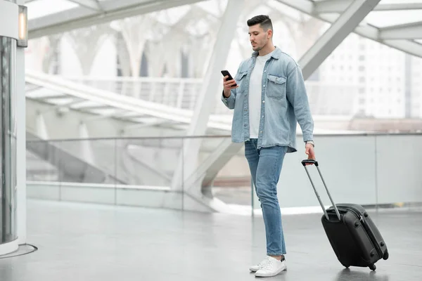 Männlicher Tourist Mit Smartphone Sms Steht Mit Reisekoffer Modernen Flughafeninneren — Stockfoto